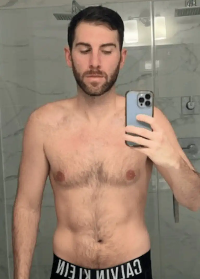 A man with short dark hair takes a selfie in a bathroom mirror, wearing black Calvin Klein underwear, showing off his workout progress like a dedicated personal trainer.