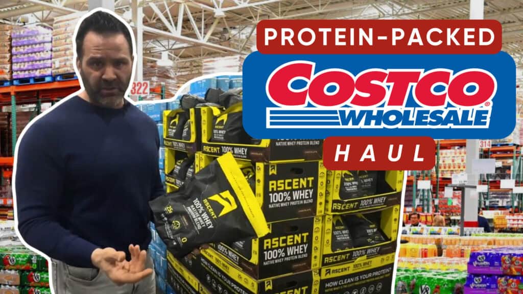 A person stands in Costco holding a bag of Ascent 100% Whey Protein next to a pallet, with a "Protein-Packed Costco Wholesale Haul" sign—perfect for your fitness or workout nutrition needs.