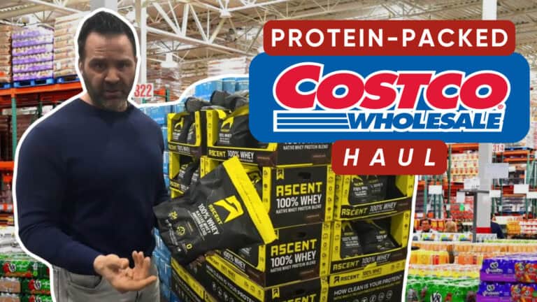 A person stands in Costco holding a bag of Ascent 100% Whey Protein next to a pallet, with a "Protein-Packed Costco Wholesale Haul" sign—perfect for your fitness or workout nutrition needs.