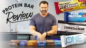 A man stands in a kitchen behind a counter with various protein bars, highlighting "Protein Bar Review" and images of different packages, perfect for anyone focused on training and nutrition.