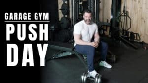 Man sitting on a bench in a garage gym with weights nearby; large text on the left reads "Garage Gym Push Day." Perfect for those seeking fitness motivation or wanting a new workout from a personal trainer.