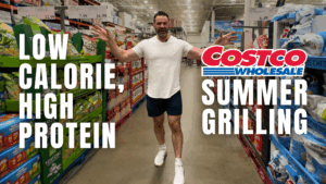 A man in a white shirt and shorts walks down a Costco aisle lined with various products. The text reads: "Low Calorie, High Protein Costco Wholesale Summer Grilling for your fitness and nutrition goals.